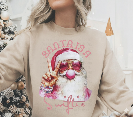 Neutral sweatshirt with a pink aesthetic Santa wearing sunglasses, blowing bubblegum, and holding a peace sign, text reads ‘Santa Is a Sweetie.